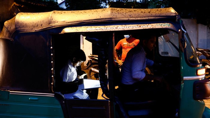 A schoolboy studies while waiting in a queue with his father to buy petrol due to fuel shortage, amid the country's economic crisis, in Colombo, Sri Lanka, June 16, 2022. REUTERS/Dinuka Liyanawatte
