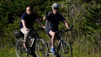 Potret Presiden AS Joe Biden menyapa sejumlah orang saat mengendarai sepeda di Pantai Rehoboth, Delaware, AS. 