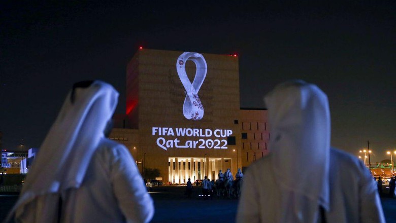 Logo Piala Dunia 2022 TOPSHOT - Qataris gather at the capital Dohas traditional Souq Waqif market as the official logo of the FIFA World Cup Qatar 2022 is projected on the front of a building on September 3, 2019. (Photo by - / AFP) (Photo credit should read -/AFP via Getty Images)