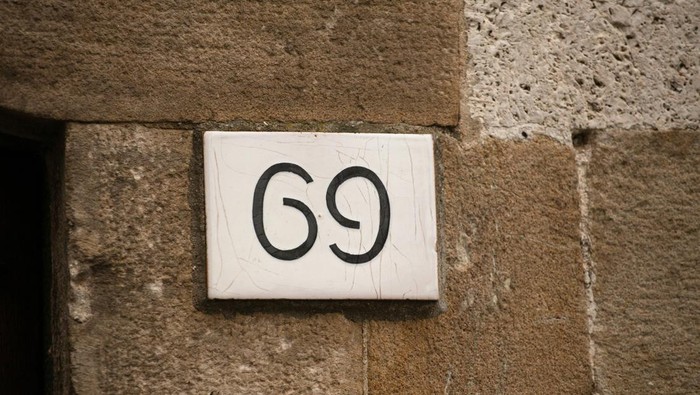 House number on brick old wall. Sexy 69 license plate on the wall of ancient building. Yin yang concept.