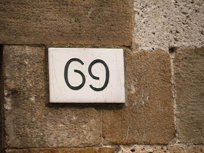 House number on brick old wall. Sexy 69 license plate on the wall of ancient building. Yin yang concept.