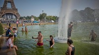 Terlihat sejumlah warga memanfaatkan kolam dengan air mancur di depan Menara Eiffel untuk mendinginkan badan.