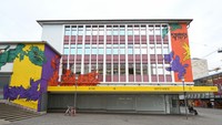 Ini bagian depan RuruHaus yang dihiasi dengan mural berwarna dan logo documenta yang berada di pusat kota.  Foto: AFP via Getty Images/ANTON ROLAND LAUB
