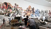 Seniman lumbung kolektif Indonesia mengerjakan mesin cetak karya Baan Noorg Collaborative Arts and Culture Thailand di documenta Halle.  Foto: AFP via Getty Images/ANTON ROLAND LAUB
