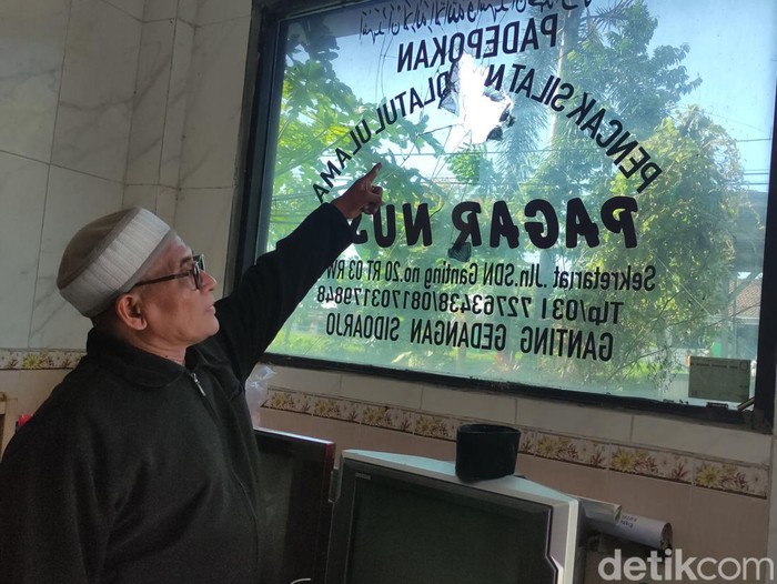Edi menunjukan kaca rumahnya yang pecah dilempar orang