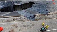 Sejumlah pekerja tampak beraktivitas di sekitar sinkhole yang muncul di tengah jalan di kawasan Villa Nueva, Guatemala. 