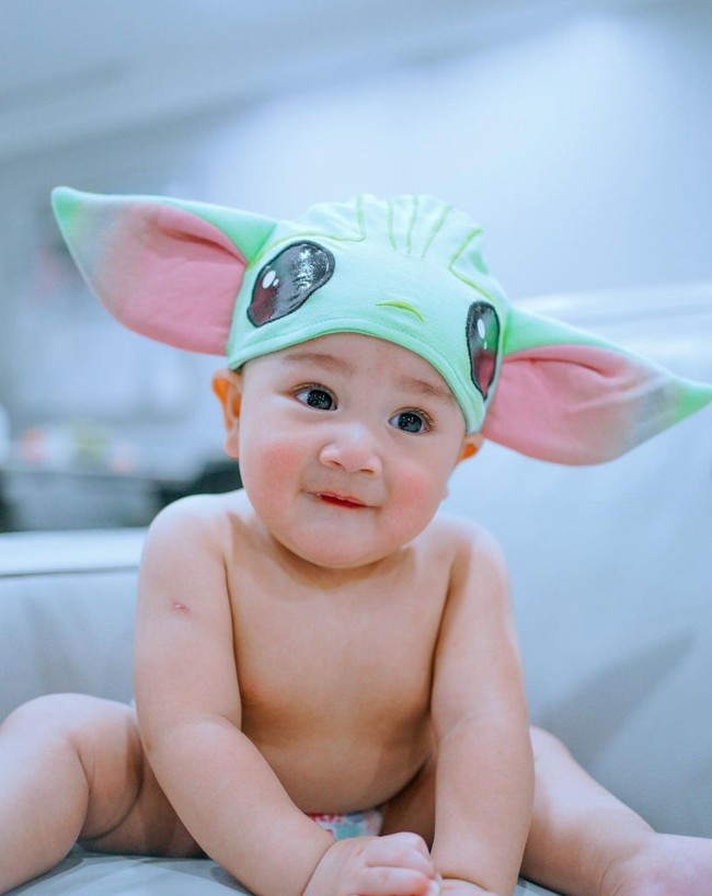 Nagita pun beberapa kali terlihat mendandani anaknya itu dengan kostum-kostum lucu. Seperti dalam foto yang satu ini ketika Rayyanza didandani mengenakan topi karakter Baby Yoda. Bikin pengin cubit kan? Foto: Instagram/@raffinagita1717