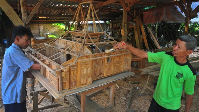 Seorang perajin menyelesaikan pembuatan miniatur rumah adat Kudus. Kerajinan miniatur rumah adat itu dibanderol puluhan juta lho. Yuk, lihat pembuatannya.