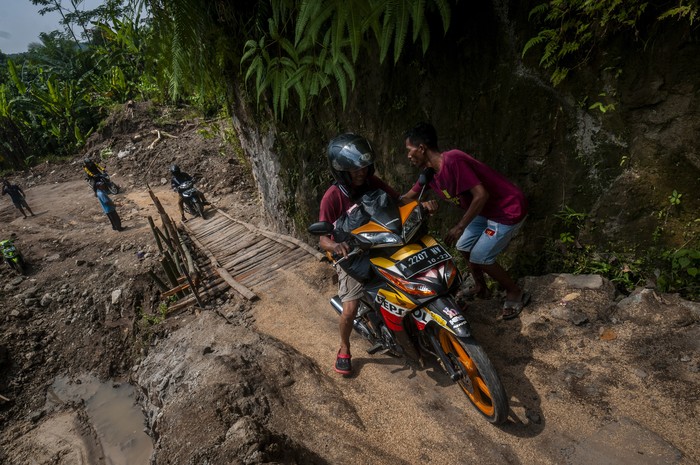 JALAN DARURAT SWADAYA MASYARAKAT Pengendara roda dua melintasi jalan darurat yang dibangun swadaya di Cikulur, Lebak, Banten, Senin (20/6/2022). Sejak dua pekan terakhir jalan yang menghubungkan Kabupaten Lebak dan Pandeglang tersebut kondisinya rusak parah akibat tanah amblas sehingga warga setempat berinisiatif membangun jalan darurat secara swadaya untuk lalu lintas warga. ANTARA FOTO/Muhammad Bagus Khoirunas/rwa.