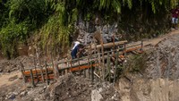 Pengendara roda dua melintasi jalan darurat yang dibangun swadaya di Cikulur, Lebak, Banten, Senin (20/6/2022).