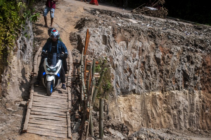 JALAN DARURAT SWADAYA MASYARAKAT Pengendara roda dua melintasi jalan darurat yang dibangun swadaya di Cikulur, Lebak, Banten, Senin (20/6/2022). Sejak dua pekan terakhir jalan yang menghubungkan Kabupaten Lebak dan Pandeglang tersebut kondisinya rusak parah akibat tanah amblas sehingga warga setempat berinisiatif membangun jalan darurat secara swadaya untuk lalu lintas warga. ANTARA FOTO/Muhammad Bagus Khoirunas/rwa.