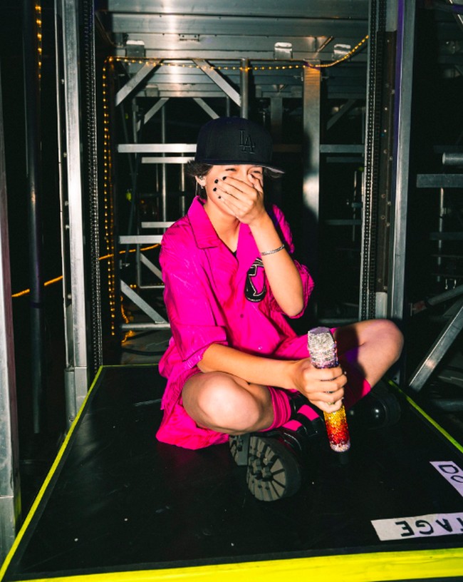 Gaya Emme di panggung acara amal tersebut terlihat cukup tomboy. Dia mengenakan setelan kemeja dan celana pendek warna pink. Emme pun terlihat mengenakan topi. Foto: dok. Twitter