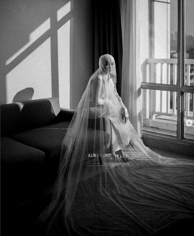 Usai akad nikah, eks personel girlband Blink ini berganti busana dengan memakai gaun warna putih bahan satin yang membentuk tubuh, dilengkapi weil wedding dengan tulisan bordir Always and forevermore. Busana resepsi Sivia juga rancangan Angelita Nurhadi dari Hands by Jeje.  Foto: Dok. Instagram @bonjoabadi of @terralogical.