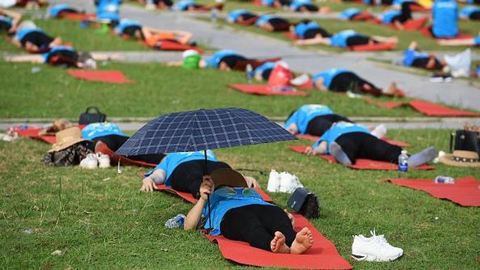 A yoga practitioner uses umbrella during a mass yoga session to mark International Yoga Day in Ha Long Bay in Quang Ninh province on June 21, 2022. (Photo by Nhac NGUYEN / AFP) (Photo by NHAC NGUYEN/AFP via Getty Images)