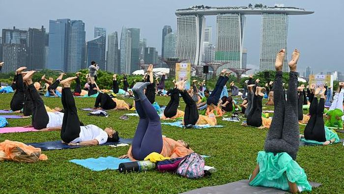 People practice yoga at an event for International Yoga Day at the Marina Barrage green rooftop in Singapore on June 21, 2022. (Photo by Roslan RAHMAN / AFP) (Photo by ROSLAN RAHMAN/AFP via Getty Images)