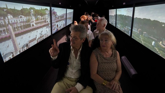 Jelajah Kota Roma Kuno dengan Virtual Bus di Italia, Mau Ikut? Journalists participating in the first tour of the Imperial Rome - Virtual Reality Bus look at 3D VR images of ancient Rome during the project presentation to the media in downtown Rome, Tuesday, June 21, 2022. The virtual tour of ancient Rome, includes the Roman Forum, the Colosseum, the Palatine Hill, the Circus Maximus, and the Theater of Marcellus, in a 3D immersion with special