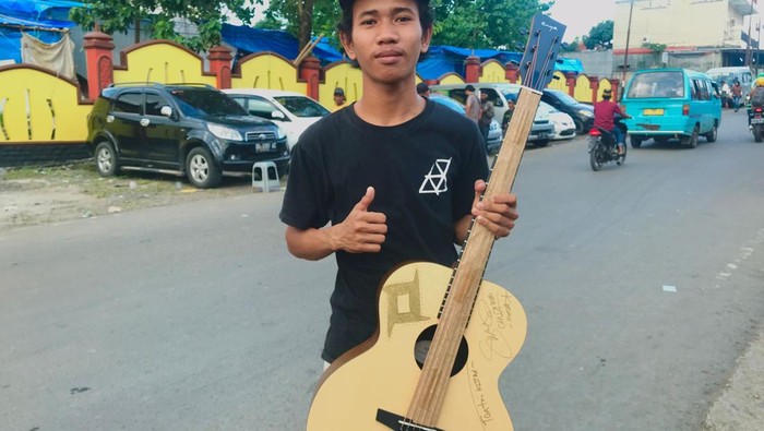 Pengamen Asrianto memarkan gitar pemberian Tantri Kotak.