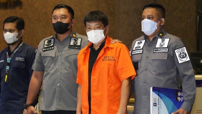 Potret Buronan Jepang Mitsuhiro Taniguchi Dideportasi dari Indonesia Immigration officers escort Japanese fugitive Mitsuhiro Taniguchi, center, who was arrested on Sumatra island in early June, prior to his deportation in Jakarta, Indonesia, Wednesday, June 22, 2022. Indonesia on Wednesday deported Taniguchi who was wanted by Japanese police for COVID-19 subsidy fraud. (AP Photo/Dita Alangkara)