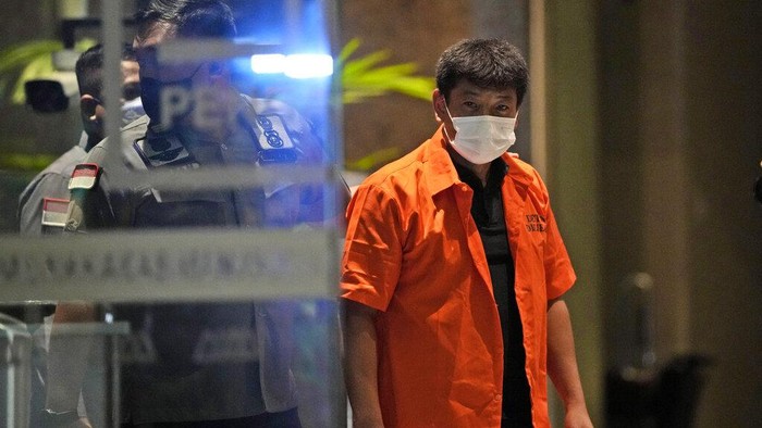 Immigration officers escort Japanese fugitive Mitsuhiro Taniguchi, center, who was arrested on Sumatra island in early June, prior to his deportation in Jakarta, Indonesia, Wednesday, June 22, 2022. Indonesia on Wednesday deported Taniguchi who was wanted by Japanese police for COVID-19 subsidy fraud. (AP Photo/Dita Alangkara)