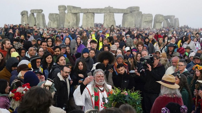 Potret Perayaan Terbitnya Matahari Musim Panas di Stonehenge Arthur Uther Pendragon, center, joins people as they gather at the Heel Stone during sunrise for the Summer Solstice festivities at Stonehenge in Wiltshire, England, Tuesday, June 21, 2022. After two years of closure due to the COVID-19 pandemic, Stonehenge reopened Monday for the Summer Solstice celebrations. (Andrew Matthews/PA via AP)