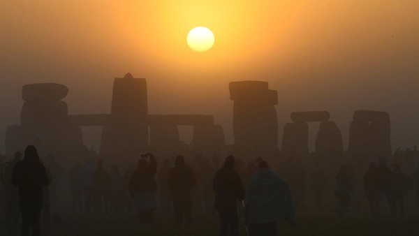 Orang-orang bersuka ria berkumpul untuk merayakan Titik Balik Matahari Musim Panas saat matahari terbit di lingkaran batu Stonehenge dekat Amesbury, Inggris, Selasa, (21/6/2022). REUTERS/Toby Melville
