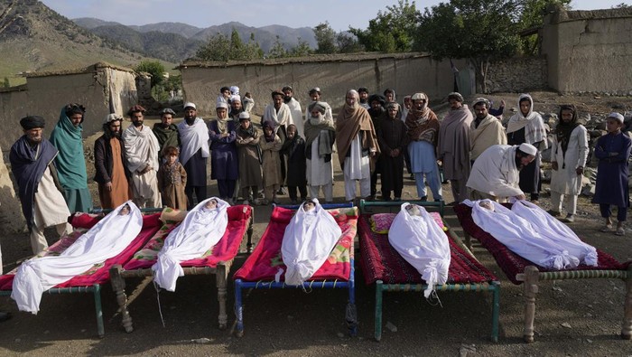 2.000 Rumah Hancur Imbas Gempa Bumi Afghanistan Men stand around the bodies of people killed in an earthquake in Gayan village, in Paktika province, Afghanistan, Thursday, June 23, 2022. A powerful earthquake struck a rugged, mountainous region of eastern Afghanistan early Wednesday, flattening stone and mud-brick homes in the country's deadliest quake in two decades, the state-run news agency reported. (AP Photo/Ebrahim Nooroozi)