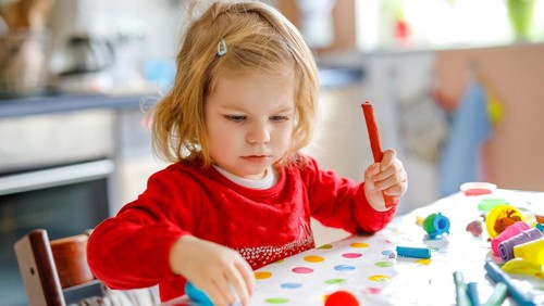 Adorable cute little toddler girl with colorful clay. Healthy baby playing and creating toys from play dough. Small kid molding modeling clay and learning.
