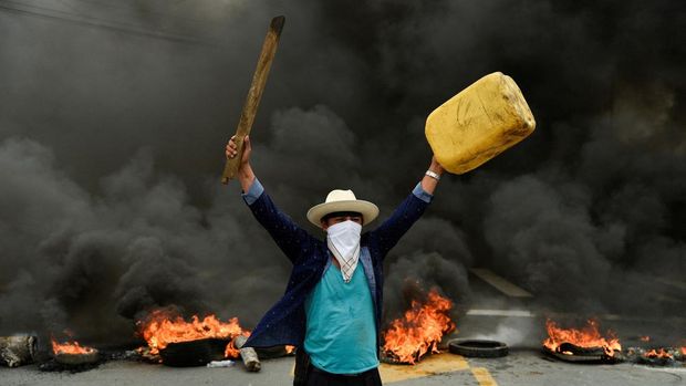 A protester gestures in front of a burning roadblock on a highway to Guayaquil during continuing demonstrations against the government of President Guillermo Lasso due to price increases for fuel, food and other basics, in Limonal, Ecuador June 22, 2022. REUTERS/Vicente Gaibor del Pino     TPX IMAGES OF THE DAY