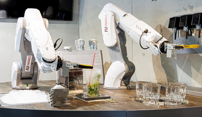 A robot places a drinking straw into a mojito cocktail at the Sausalitos bar in Munich, Germany, June 21, 2022. The robot, which consists of two arms, is designed to relieve the bar staff by mixing cocktails fully automatically.  REUTERS/Lukas Barth
