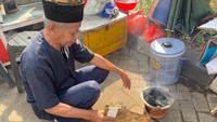 Sebelum mulai masak, penjual kerak telor bernama Pak Murtaha menyiapkan arang yang dikipas-kipas agar cepat panas. Foto: Detikcom