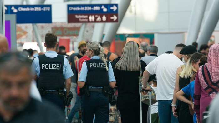 polices are seen patrolling among the Travellers who are seen waiting in a long line at a security check point at Duesseldorf airport in Duesseldorf, Germany on June 22, 2022 as staff shortages continues causes the airport chaos during the holiday season (Photo by Ying Tang/NurPhoto via Getty Images)