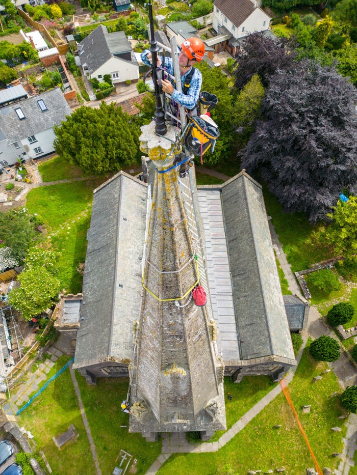 1404647766 UFFCULME, ENGLAND - JUNE 23: Arthur Needham from Vitruvius Building Conservation paints the lightning conductor on the steeple as part of restoration work at the top of St Maryβs Church, on June 23, 2022 in Uffculme, United Kingdom. (Photo by Finnbarr Webster/Getty Images)