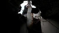Seorang petugas mengeluarkan bom yang telah dijinakkan untuk dipindakan dari atap gedung apartemen yang menjadi sasaran serangan di tengah perang Rusia-Ukraina di Kharkiv.