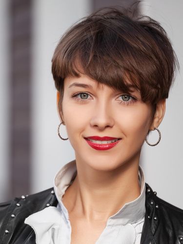 Happy young fashion woman in leather jacket walking in city street