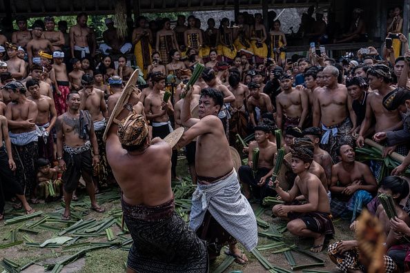 BALI, INDONESIA - JUNE 23: Two Balinese men fight each other using pandanus leaf and rattan shield during the pandanus war ritual called Mekare-kare on June 23, 2022 in Tenganan Pegringsingan Village, Bali, Indonesia. The ancient 