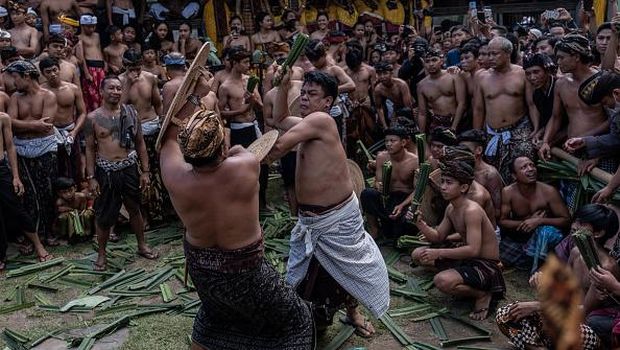 BALI, INDONESIA - JUNE 23: Two Balinese men fight each other using pandanus leaf and rattan shield during the pandanus war ritual called Mekare-kare on June 23, 2022 in Tenganan Pegringsingan Village, Bali, Indonesia. The ancient 