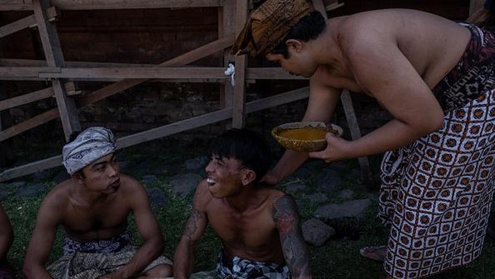 BALI, INDONESIA - JUNE 23: Two Balinese men fight each other using pandanus leaf and rattan shield during the pandanus war ritual called Mekare-kare on June 23, 2022 in Tenganan Pegringsingan Village, Bali, Indonesia. The ancient 