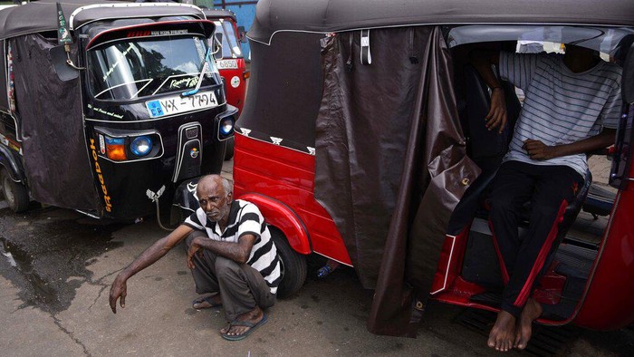 A man holds a cup of tea and walks past autorickshaws waiting in a queue to fill fuel in Colombo, Sri Lanka, Friday, June 24, 2022. Sri Lankans have endured months of shortages of food, fuel and other necessities due to the country’s dwindling foreign exchange reserves and mounting debt, worsened by the pandemic and other longer term troubles. (AP Photo/Eranga Jayawardena)