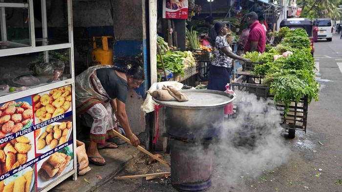 A man holds a cup of tea and walks past autorickshaws waiting in a queue to fill fuel in Colombo, Sri Lanka, Friday, June 24, 2022. Sri Lankans have endured months of shortages of food, fuel and other necessities due to the country’s dwindling foreign exchange reserves and mounting debt, worsened by the pandemic and other longer term troubles. (AP Photo/Eranga Jayawardena)