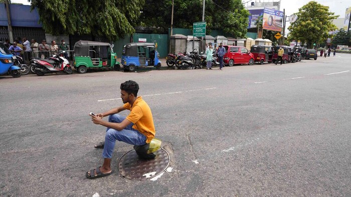 Potret Terkini Setelah Sri Lanka Dinyatakan Bangkrut A man holds a cup of tea and walks past autorickshaws waiting in a queue to fill fuel in Colombo, Sri Lanka, Friday, June 24, 2022. Sri Lankans have endured months of shortages of food, fuel and other necessities due to the country’s dwindling foreign exchange reserves and mounting debt, worsened by the pandemic and other longer term troubles. (AP Photo/Eranga Jayawardena)