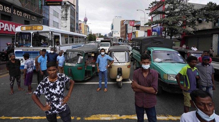 A man holds a cup of tea and walks past autorickshaws waiting in a queue to fill fuel in Colombo, Sri Lanka, Friday, June 24, 2022. Sri Lankans have endured months of shortages of food, fuel and other necessities due to the country’s dwindling foreign exchange reserves and mounting debt, worsened by the pandemic and other longer term troubles. (AP Photo/Eranga Jayawardena)