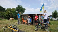 Rumah-rumahan tersebut juga dipasangi bendera Ukraina. Anak-anak begitu gembira bermain di sekitar rumah-rumahan yang terbuat dari peti bekas amunisi itu.