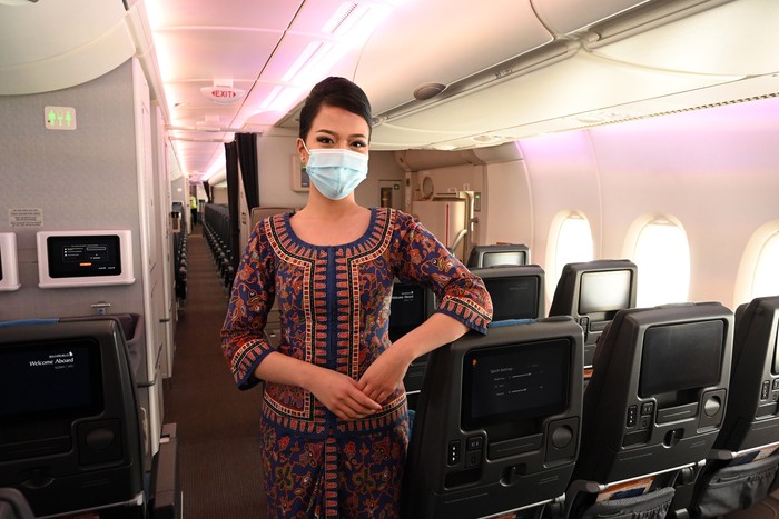 A Singapore Airlines stewardess poses along the aisle during a media tour onboard a Singapore Airlines Airbus A380 at Changi International Airport in Singapore on October 24, 2020. (Photo by ROSLAN RAHMAN / AFP) (Photo by ROSLAN RAHMAN/AFP via Getty Images)