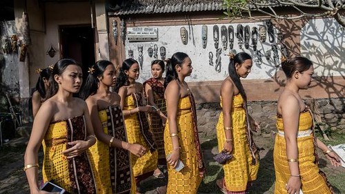 BALI, INDONESIA - JUNE 23: Women from Indigenous community of Tenganan Pegringsingan ride ancient spinning wheels called Ayunan Jantra after the Pandanus war ritual called Mekare-Kare on June 23, 2022 in Tenganan Pegringsingan Village, Bali, Indonesia. The ancient 