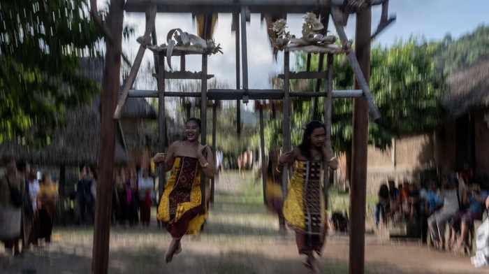 Serunya Tradisi Ayunan Jantra di Desa Tenganan Bali BALI, INDONESIA - JUNE 23: Women from Indigenous community of Tenganan Pegringsingan ride ancient spinning wheels called Ayunan Jantra after the Pandanus war ritual called Mekare-Kare on June 23, 2022 in Tenganan Pegringsingan Village, Bali, Indonesia. The ancient