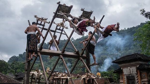 BALI, INDONESIA - JUNE 23: Women from Indigenous community of Tenganan Pegringsingan ride ancient spinning wheels called Ayunan Jantra after the Pandanus war ritual called Mekare-Kare on June 23, 2022 in Tenganan Pegringsingan Village, Bali, Indonesia. The ancient 