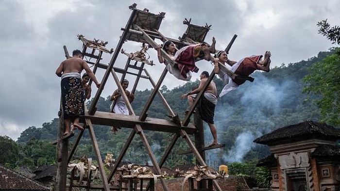 Serunya Tradisi Ayunan Jantra di Desa Tenganan Bali BALI, INDONESIA - JUNE 23: Women from Indigenous community of Tenganan Pegringsingan ride ancient spinning wheels called Ayunan Jantra after the Pandanus war ritual called Mekare-Kare on June 23, 2022 in Tenganan Pegringsingan Village, Bali, Indonesia. The ancient