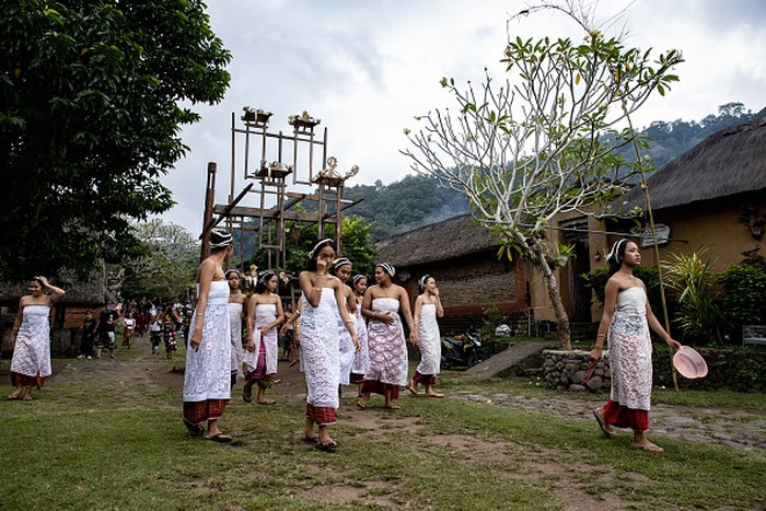 BALI, INDONESIA - JUNE 23: Women from Indigenous community of Tenganan Pegringsingan ride ancient spinning wheels called Ayunan Jantra after the Pandanus war ritual called Mekare-Kare on June 23, 2022 in Tenganan Pegringsingan Village, Bali, Indonesia. The ancient Bali Aga Tenganan Pegringsingan village is different from the other villages in Bali, especially in their belief in the God of Indra and Balinese culture are intertwined in the communitys daily life. The village also has its own territory and preserves its traditions in ways contrasting those found in other villages in Bali. Tengananese people on the island of Bali celebrate a month long ceremony called Usabha Sambah to demonstrate respect to the God Indra, the Hindu god of war. One of the rituals during the ceremony is a Pandanus War or Mekare Kare, where two Tengananese men duel each other to shed the blood for the offerings. The tradition originated from a belief that they have to make blood sacrifices to Indra. When the men and boys shed their blood during the battle, this is the ultimate sacrifice and devotion to Indra, and also shows dedication to their community. (Photo by Agung Parameswara/Getty Images)