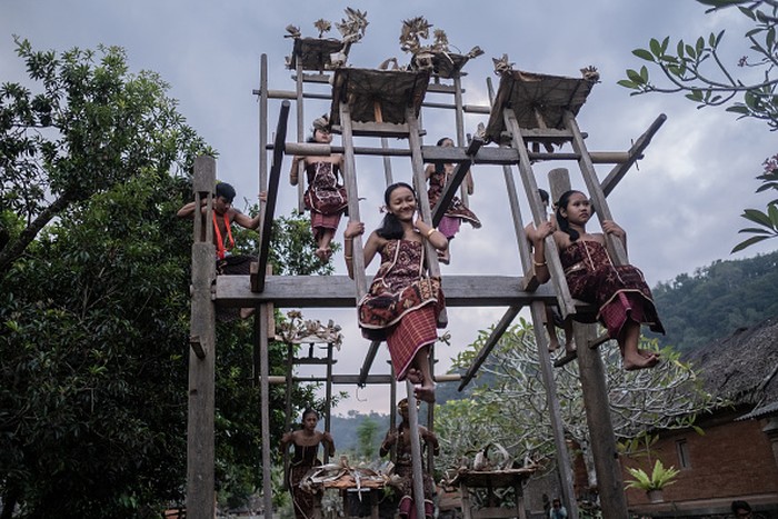BALI, INDONESIA - JUNE 23: Women from Indigenous community of Tenganan Pegringsingan ride ancient spinning wheels called Ayunan Jantra after the Pandanus war ritual called Mekare-Kare on June 23, 2022 in Tenganan Pegringsingan Village, Bali, Indonesia. The ancient 