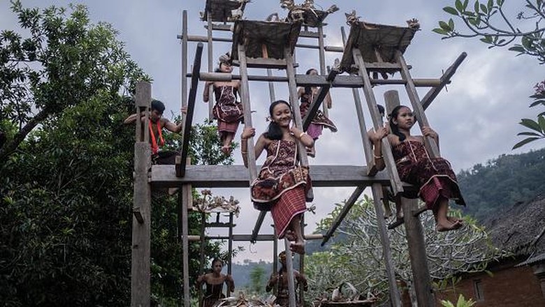 BALI, INDONESIA - JUNE 23: Women from Indigenous community of Tenganan Pegringsingan ride ancient spinning wheels called Ayunan Jantra after the Pandanus war ritual called Mekare-Kare on June 23, 2022 in Tenganan Pegringsingan Village, Bali, Indonesia. The ancient 